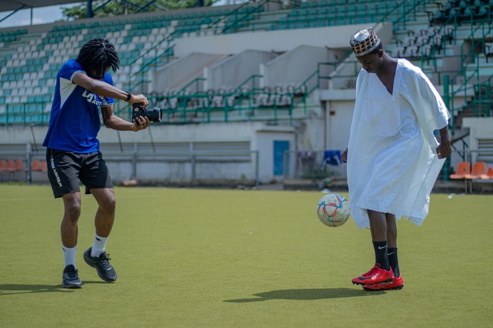 A young creator filming a player showing off skills on the pitch