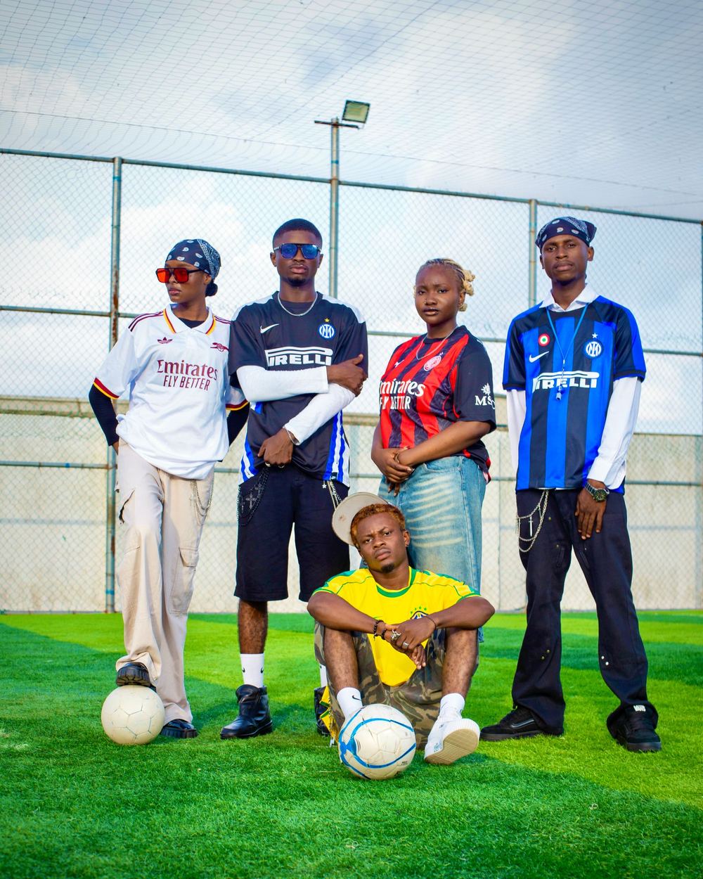 Four stylish young footballers posing on a five-a-side astro pitch